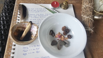 Stones, seeds, and a bowl of water, beside the affirmations I wrote before sitting down.